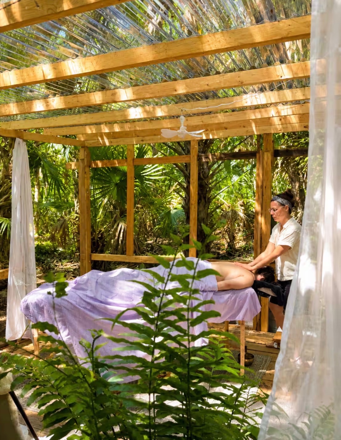 Massage table in an open-air pavilion surrounded by plants