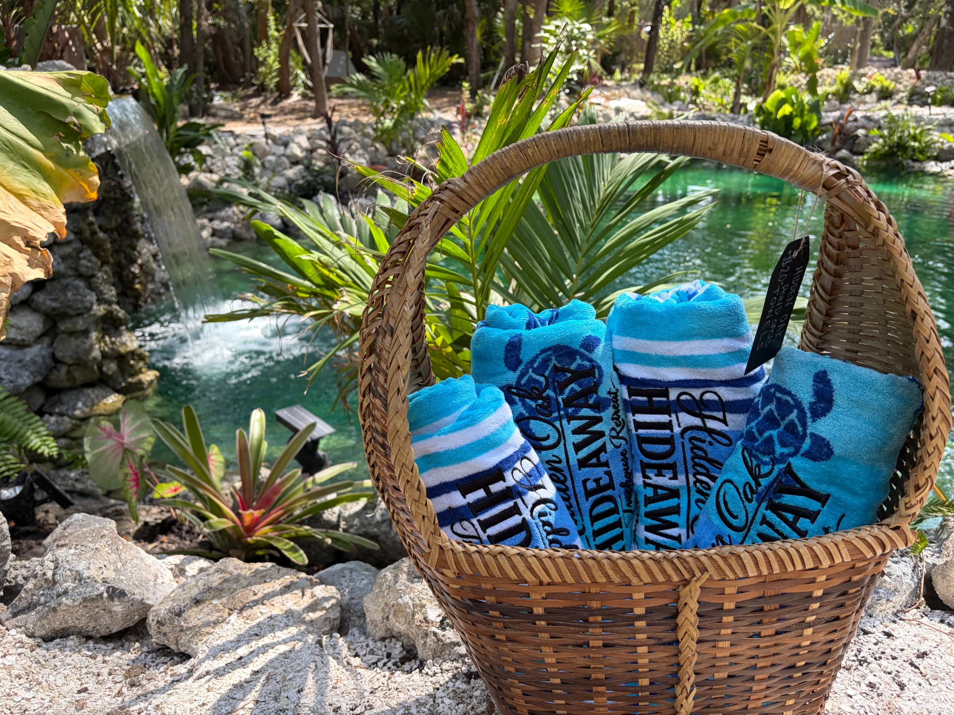 Basket of blue Hidden Oak Hideaway beach towels beside the pond